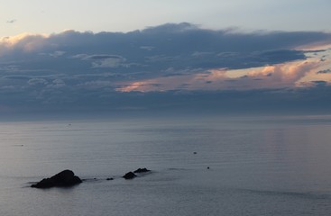 rocas en mitad del mar con la puesta de sol de fondo