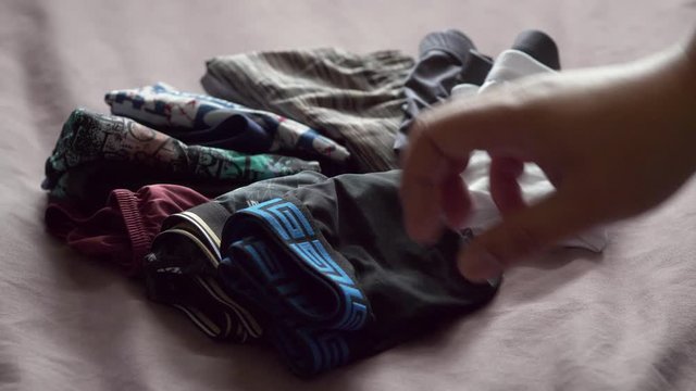 Men use their hands to fold men's underwear to keep it organized and easy to store and use. 4K, 29.97fps