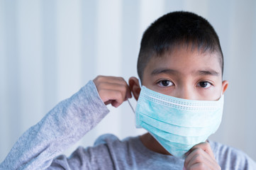 Portrait Asian kid wearing medical mask.A boy wearing mouth mask against air smog pollution. Concept of corona virus quarantine or covid-19.Protection against virus and infection control concept.