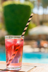 Red cocktail with ice with a straw on a on bar background. vertical photo