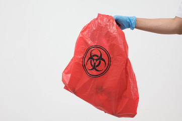 Scientist wearing blue gloves and red bag with bioharzard sign.A woman worker hand holding red...