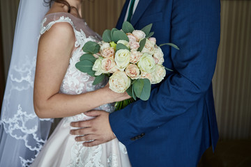 Bride holding a wedding bouquet in the hands standing near groom