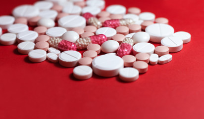 Heap of white pills, tablets, capsules on red background. Drug prescription for treatment medication health care concept wth copy space.