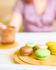 Young beautiful caucasian woman is enjoying her morning breakfast of black coffee, French macarons served on a tray. Breakfast in bed concept