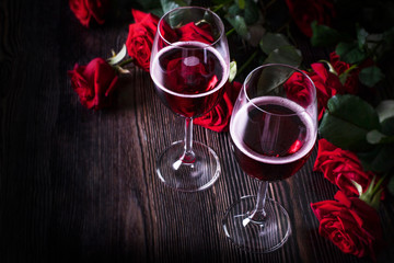 Romantic holiday, glasses with red wine and roses, dark background