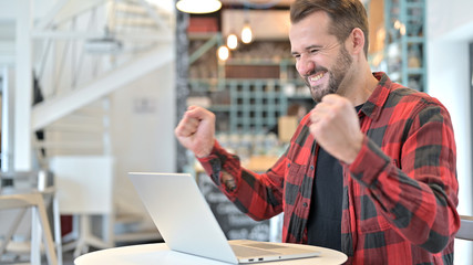 Obraz premium Beard Young Man Celebrating on Laptop in Cafe