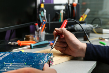 electrician hands are working with soldering iron in workshop close up