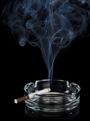 Curling smoke from one cigarette in an ashtray