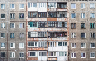 Fototapeta na wymiar Facade of a grey multi-storey soviet panel building