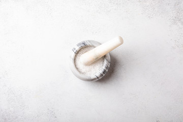 Plakat Flat lay of sea salt on marble mortar. Skin and self-care concept, top view.