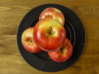 Apples on a plate on a wooden table.