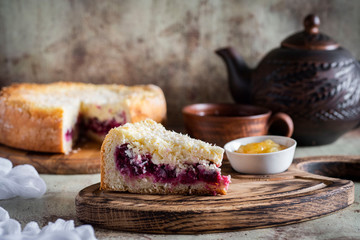A piece of cherry pie on a wooden plate in the foreground