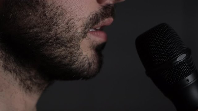 Young bearded Man talks to microphone. Man microphone speech, close up side view
