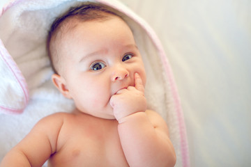 Portrait of a little newborn girl who has her  finger in mouth