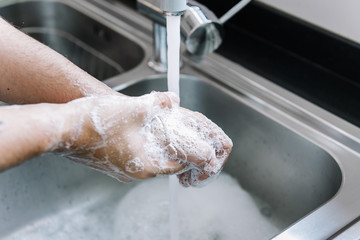 Fototapeta premium two hands of a man taking off the foam with water