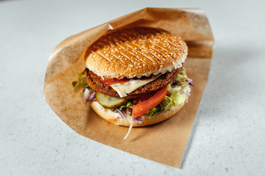 Close up view on meat burger wrapped in brown paper - Powered by Adobe