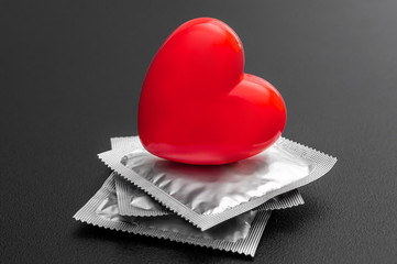 Red heart with condoms on black background. Safe sex concept.