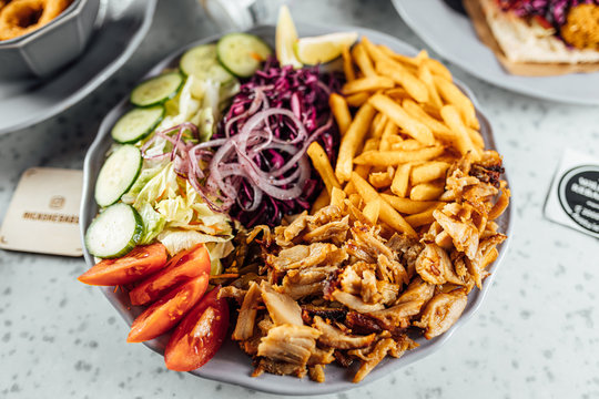 Doner Kebab on plate with vegetables fries and souce, grilled meat on plate