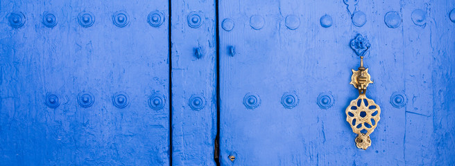 Background of traditional powder blue painted door with golde doorknocker