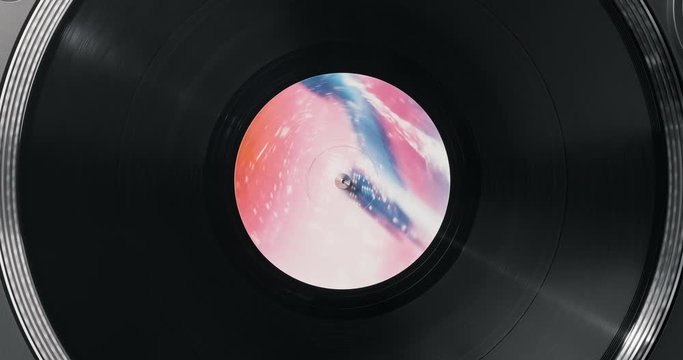 Black vinyl record on DJ player. Black vinyl background pink and blue label in center. Rotating plate close-up on turntable. Loop. Macro Top view. Popular styles of disco from 60s, 70s, 80s, 90s