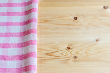 Background with checkered pink napkin on a wooden table. Copy space.
