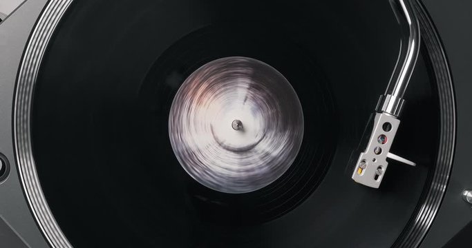 Black vinyl record on DJ player. Black vinyl background black, white label in center. Rotating plate close-up on turntable. Needle stylus. Macro Top view. Popular styles of disco 60s, 70s, 80s, 90s