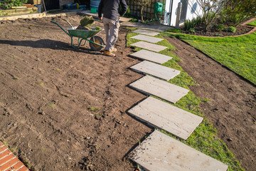 Removal of old turf around a new stepping stone walkway in preperation for the installation of a new turf lawn. - 330566769