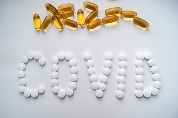 Лекарства таблетки на белом фоне белые и желтые слово ковид