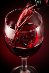 glass of red wine and bottle on black background	