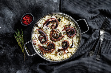 Homemade Italian risotto with octopus in a pan. Black background. Top view