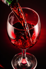 glass of red wine and bottle on black background	