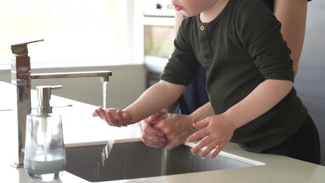 Little boy is washing hands together with his mother - she is teaching him Aboud good hygiene