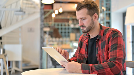 Beard Young Man using Digital Tablet in Cafe