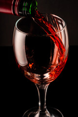 glass of red wine and bottle on black background	