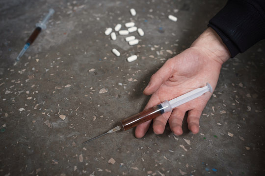 Hand of the narcotist with syringe on the floor. The concept of drug abuse, overdose.