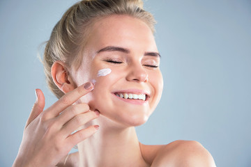moisturizing summer skin care sunscreen. beautiful model applying cosmetic cream treatment on her...