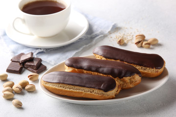 Dessert. Eclairs with chocolate glaze with a cup of coffee. Cake with cream. Chocolate, pistachios...