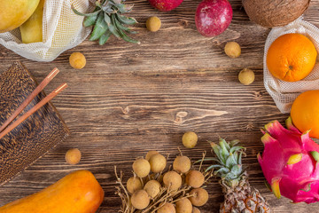 Set of exotic tropical fruits on wooden rustic background - papaya, mango, pineapple, dragon fruit, orange, coconut, passion fruit, longan. Top view. Zero waste concept