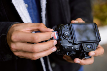 Photographer hand holds Memory card - Flash card near professional DSLR camera. Male photographer...