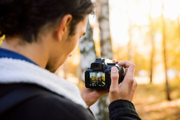 Photographer shooting video with his dslr camera outdoor in the park in sunset