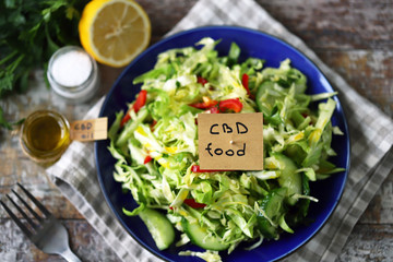 Selective focus. A note with the words cbd food in a plate with vegetable salad. Salad with the addition of CBD oil. Salad with fresh cabbage, herbs and cucumber. Vegan diet. Eco food. Cbd food.