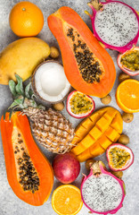 Set of exotic tropical fruits on light gray background - papaya, mango, pineapple, dragon fruit, orange, coconut, passion fruit, longan. Top view