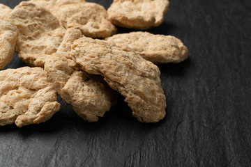 Raw Dehydrated Soy Meat or Soya Chunks on Black Stone Background