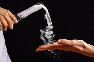 White smoke emitted from lab glass equipment on black background. Chemistry experiment in...