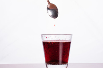 Glass of red healthy vitamin cocktail isolated on white background. Small red drop of liquid falling to glass. Diet and healthy lifestyle concept...