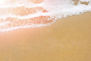 Background with copy space made of yellow sandy beach view of seashore with foamy wave. Top view of tropical beach as layout.