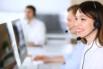 Call center. Group of diverse operators at work. Focus on beautiful asian woman in headset at customer service office. Business concept