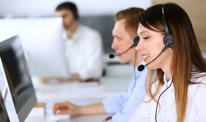 Call center. Group of diverse operators at work. Focus on beautiful asian woman in headset at customer service office. Business concept