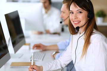 Call center. Group of diverse operators at work. Focus on beautiful asian woman in headset at customer service office. Business concept