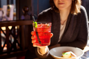 Fototapeta premium Woman holding cocktail glass with grenadine in a cafe